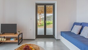 A modern living room with a television, a fruit basket, and a sofa with patterned cushions. - Vastblue (Paros)