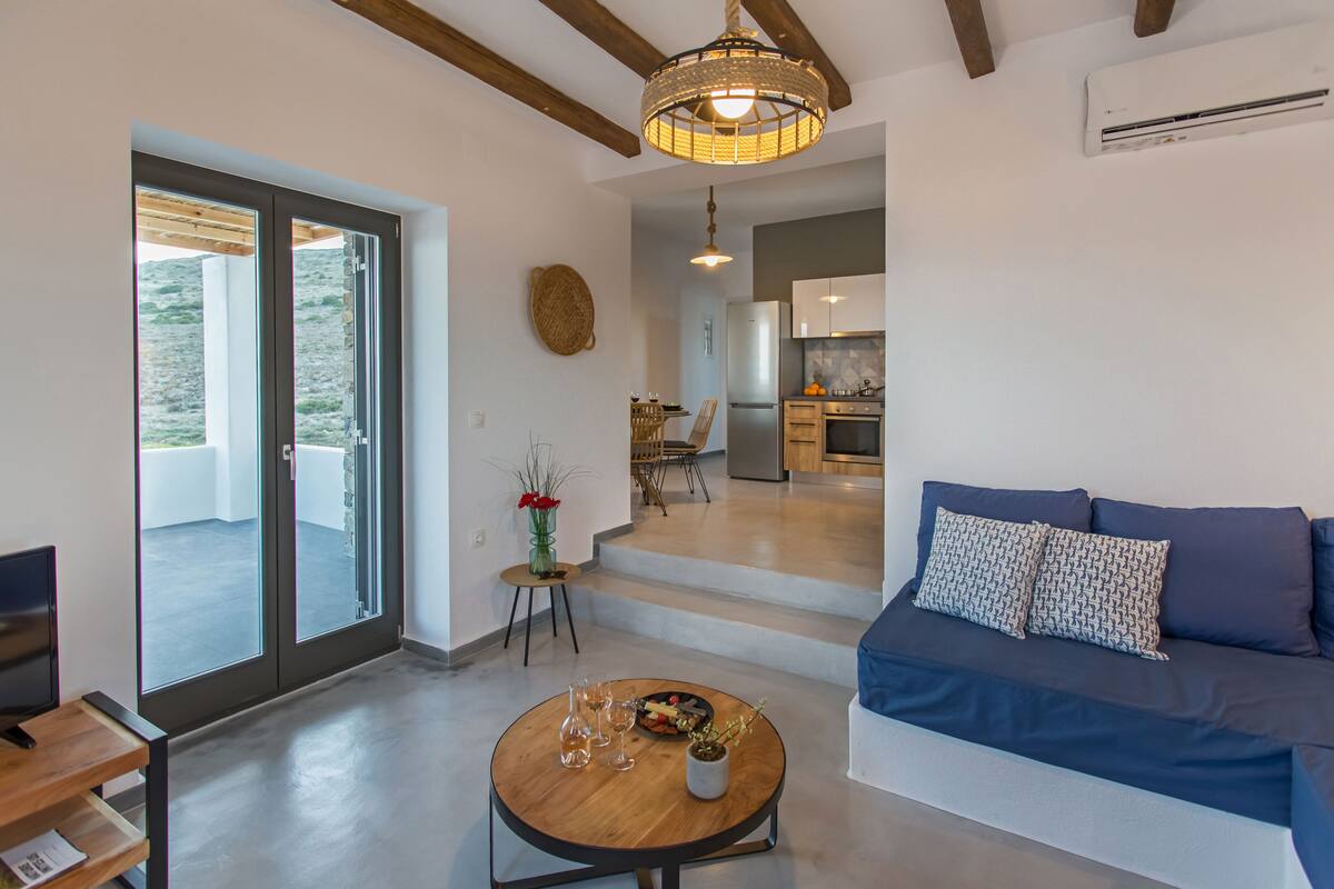A modern living room with a blue sofa, a wooden coffee table, and a glass door leading to a balcony.