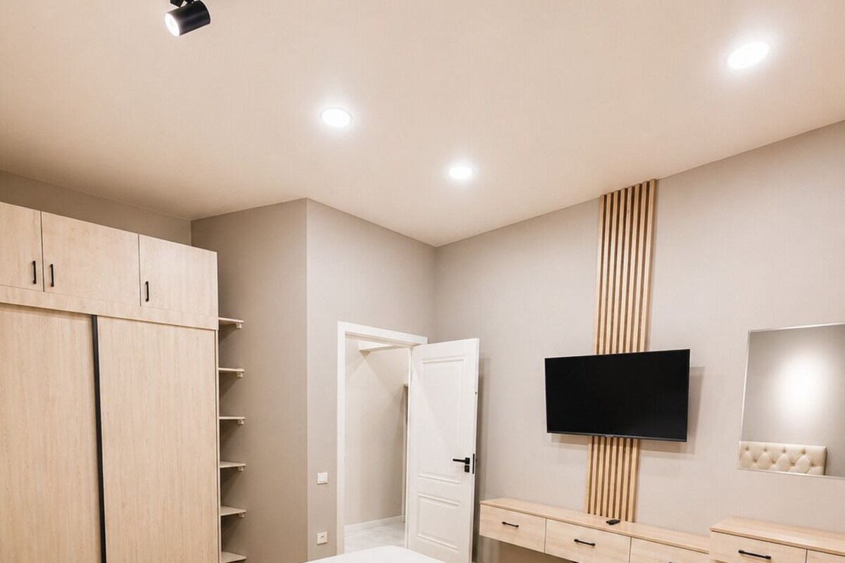 A bedroom with a bed, wardrobe, TV, and a mirror.