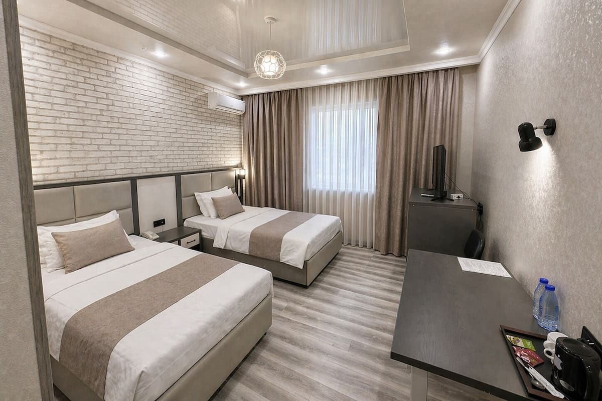 A hotel room with two beds, a desk, a TV, and a minibar.