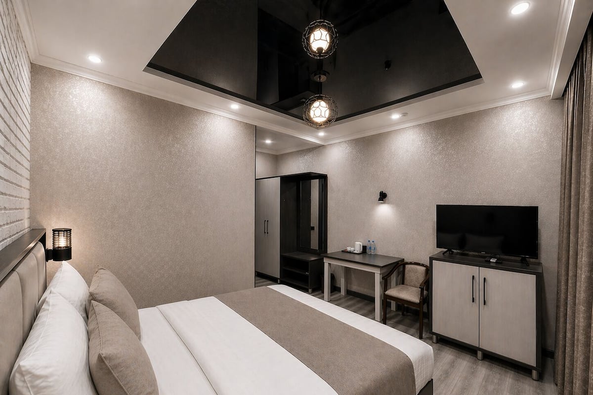 A modern hotel room with a bed, desk, TV, and wardrobe.