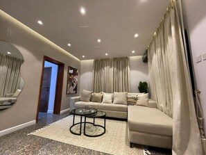 A modern living room with a sofa, coffee table, and a mirror. - Luxurious One Bedroom in the heart of Lagos! Cozy, your home away from home!! (Lekki Phase I)