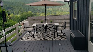 Una terraza con una mesa y sillas, una planta en maceta y vistas a un paisaje montañoso.