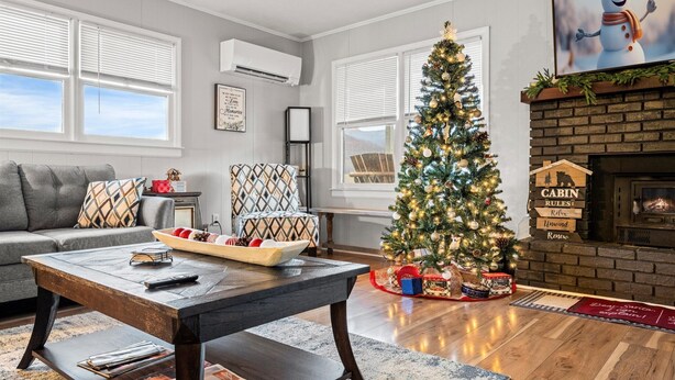 Una sala de estar acogedora con chimenea, un árbol de Navidad y un sofá.