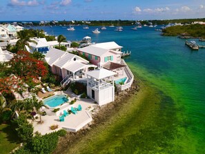 A coastal property with a swimming pool, multiple decks, and a view of the marina with boats.