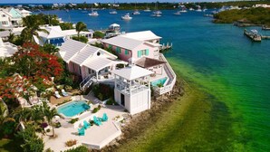 A coastal property with a swimming pool, multiple decks, and a view of the marina with boats. - Saltwater Sanctuary-Secret garden in a tropical paradise (Hope Town)