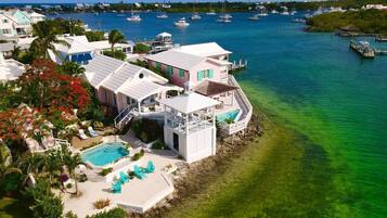 A coastal property with a swimming pool, multiple decks, and a view of the marina with boats.