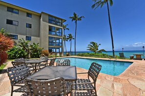 A poolside area with outdoor seating and a view of the ocean.