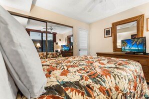 Habitación de hotel con una cama grande, televisión, espejo y ventilador de techo.