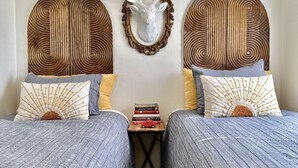 A room with two beds, each with a unique headboard design, a small table with books and a toy car, and a wall-mounted deer head decoration. - Lee’s Garden House (Oskaloosa)