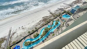 A resort with a beach, a winding pool, and a large building.