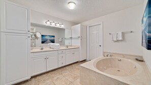 A modern bathroom with a large bathtub, a double vanity with a mirror, and a walk-in shower.
