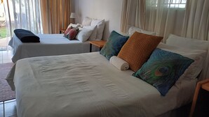 A hotel room with two beds, a small table, and a lamp.