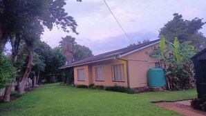 A single-story house with a sloped roof, a water tank, and a well-maintained lawn.