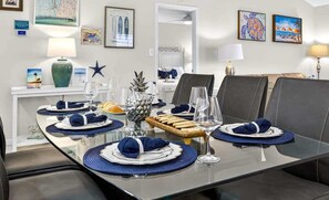 A dining area with a glass table, blue placemats, and a pineapple centerpiece.