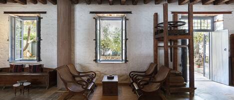 A rustic interior with wooden beams, a stone floor, and a bench with cushions.