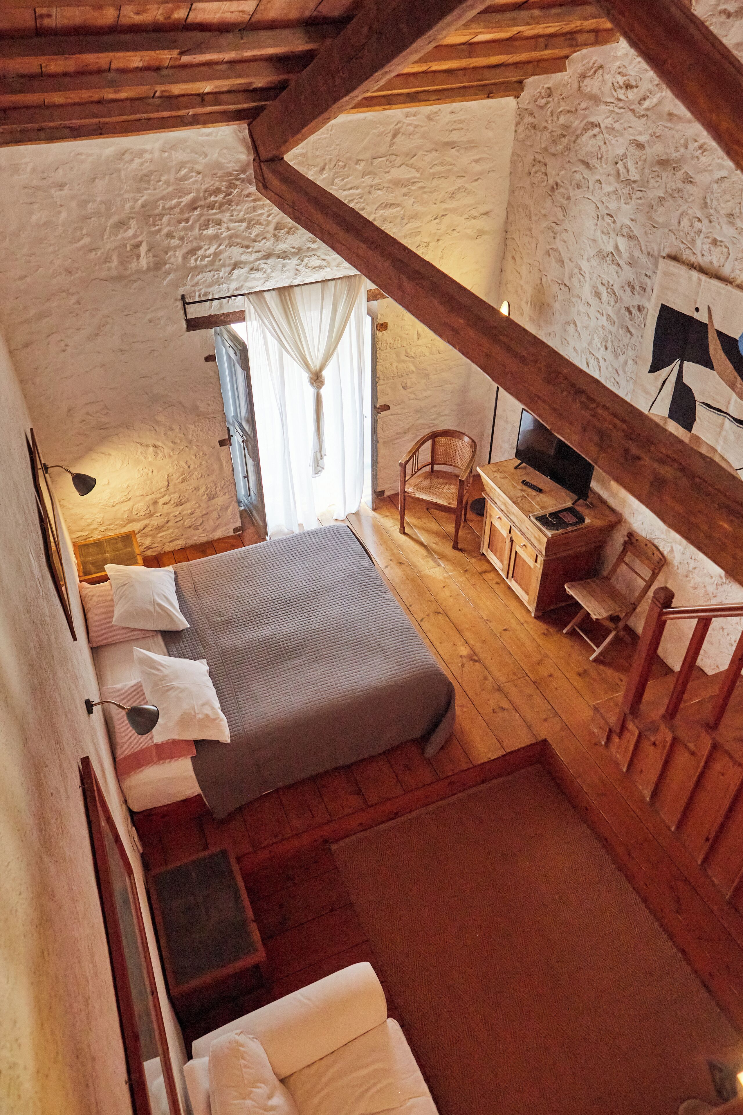A cozy room with a bed, a wooden desk, a chair, and a television.