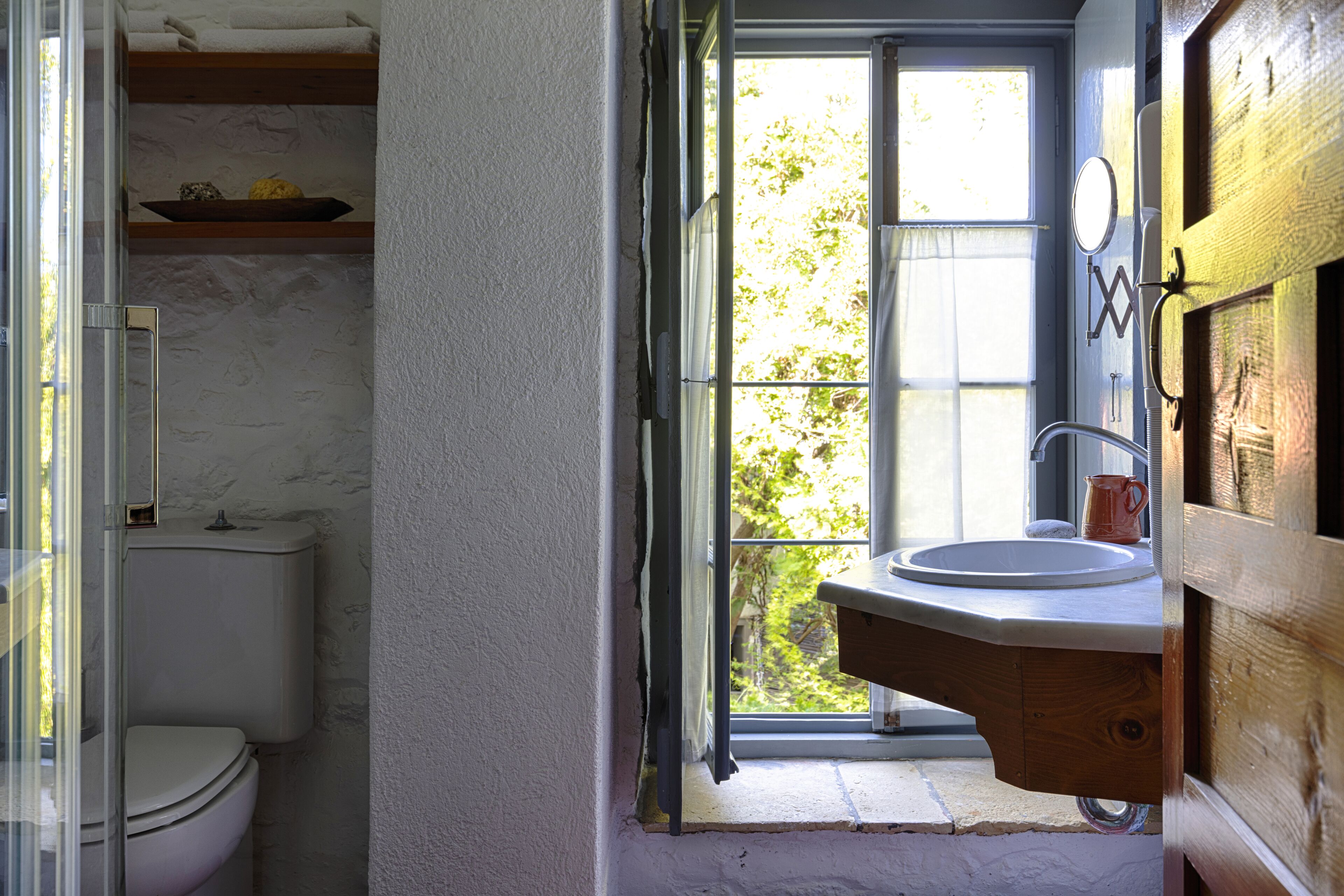 A bathroom with a toilet, a sink, and a window.