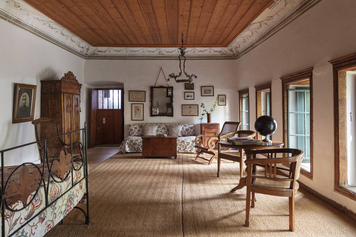 Une pièce avec un plafond en bois, un canapé, une table à manger avec des chaises et un globe terrestre.