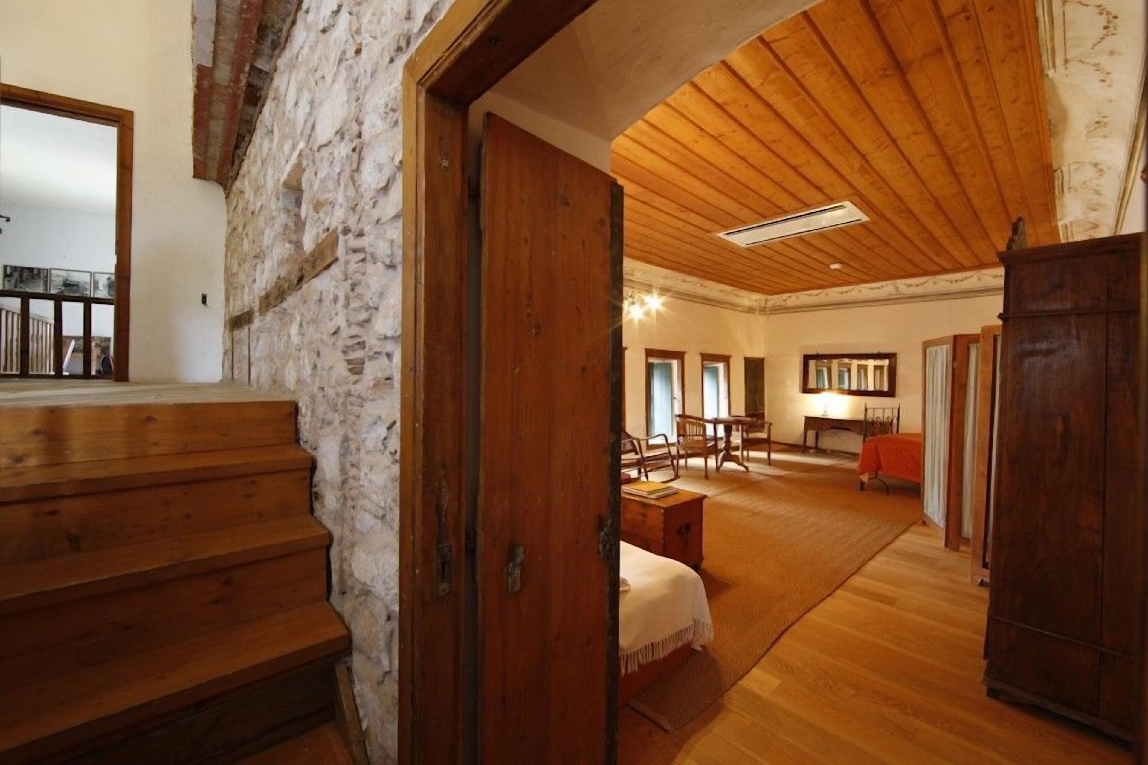 Un intérieur rustique avec des planchers en bois, un mur en pierre et un escalier menant à un balcon.