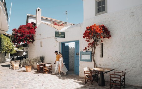 A courtyard with stone flooring, outdoor seating, and a building with a blue door.
