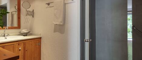 A bathroom with wooden cabinets, a sink, a mirror, and a towel rack.