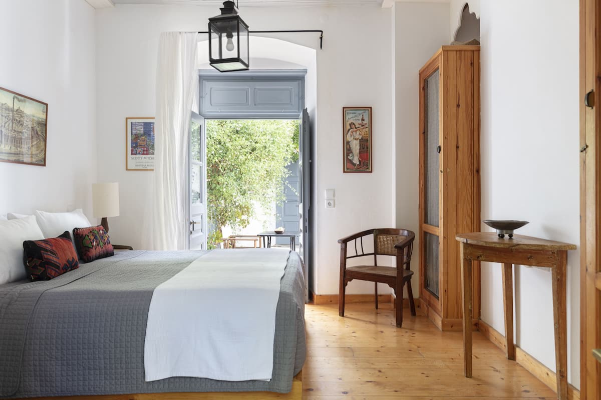 Une chambre à coucher comprenant un lit, une chaise, une table et une porte donnant sur un balcon.