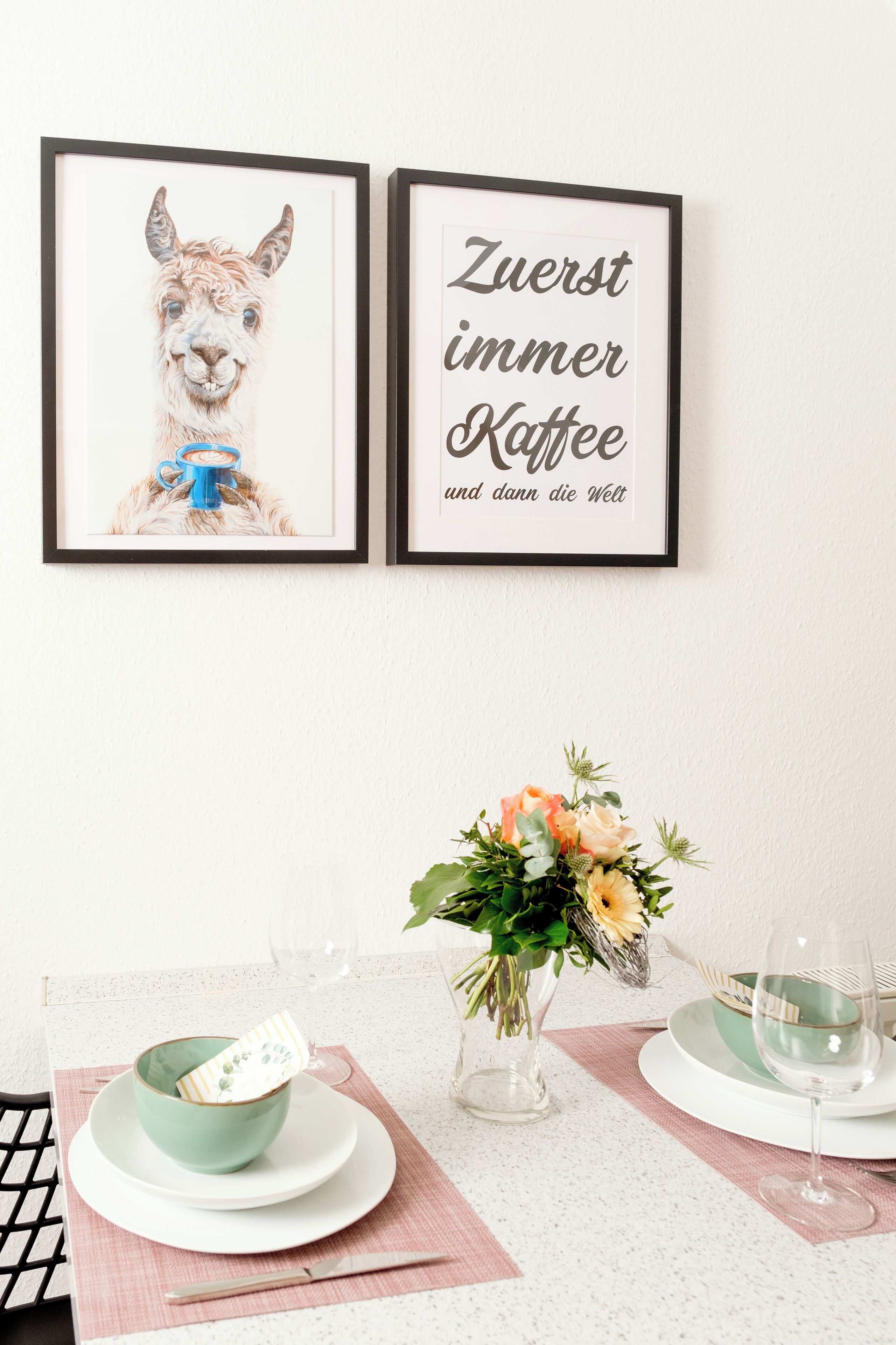 Une table à manger ornée d’un tableau encadré représentant un lama et d’une citation encadrée en allemand.