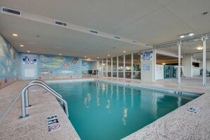 An indoor swimming pool with a mural, clear signage, and a lifeguard duty notice.