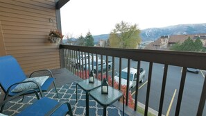 Ein Balkon mit blauen Stühlen, einem kleinen Tisch und einem hängenden Blumentopf.