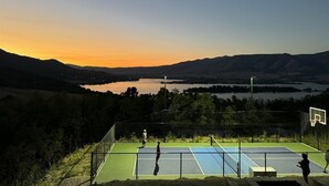 An outdoor basketball court with a view of a lake and mountains. - The Pickleball Gathering Place (Huntsville)