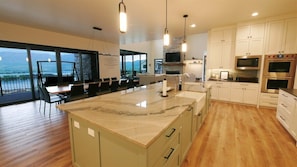 A modern kitchen with a large island, built-in appliances, and a view of the outdoors.
