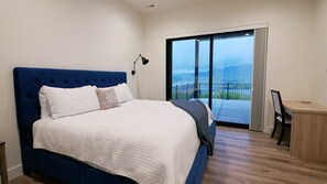 A bedroom with a large bed, a desk, and a view through a sliding glass door. - The Pickleball Gathering Place (Huntsville)