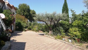 A paved pathway leading to a building with a stone facade and a metal gate. - Maison Provençale Familiale, Avec Jardin et Parking, 1, Proche Plage (Saint-Cyr-sur-Mer)