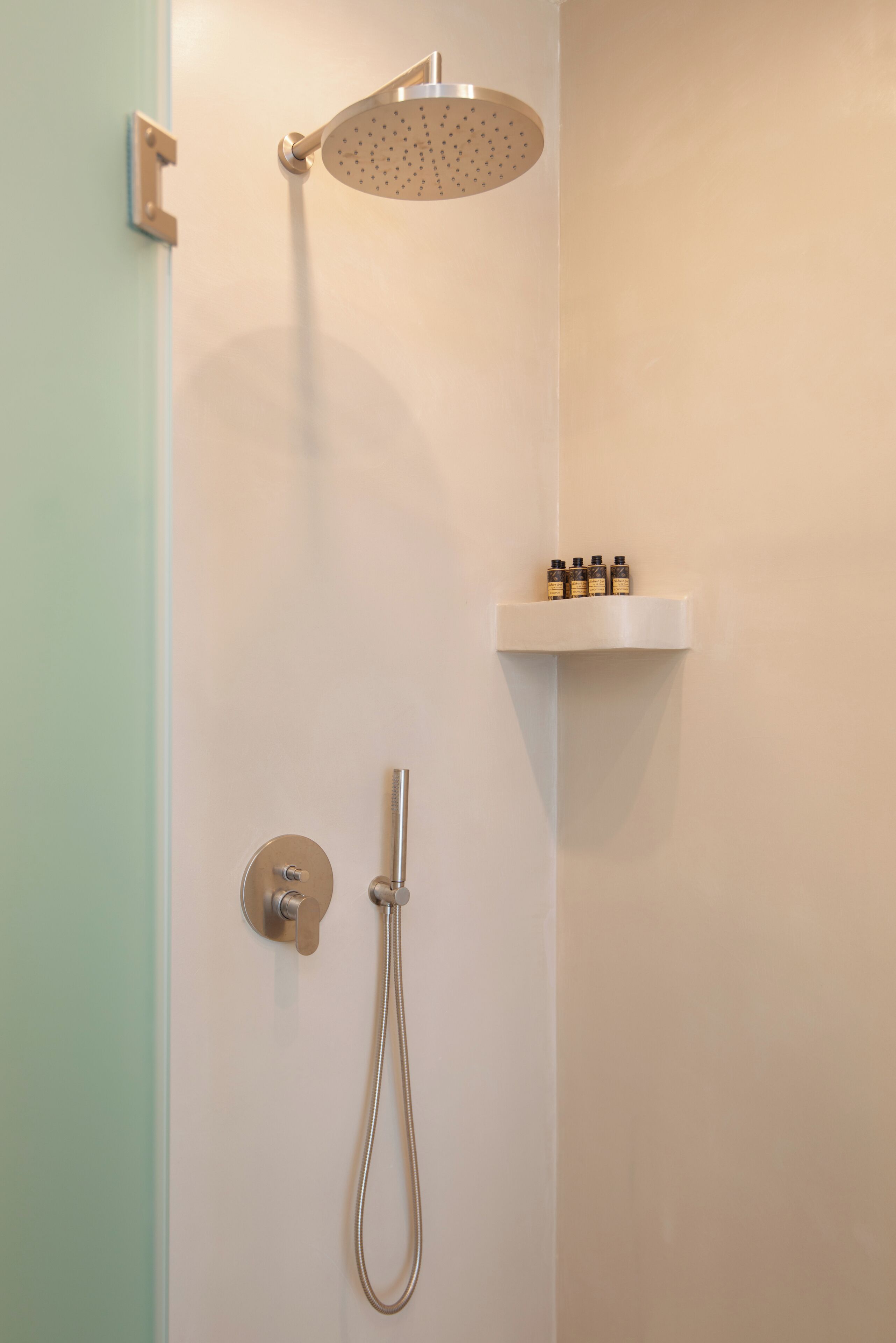 Een douche met een handdouche en een wandmengkraan.