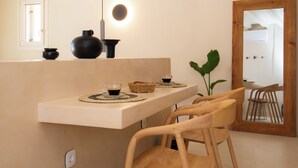 A modern kitchen with a wooden counter, stools, and a hanging light fixture. - Filadaki Villas (Sifnos)