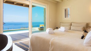 A bedroom with a bed, towels, and a view of the ocean. - Filadaki Villas (Sifnos)