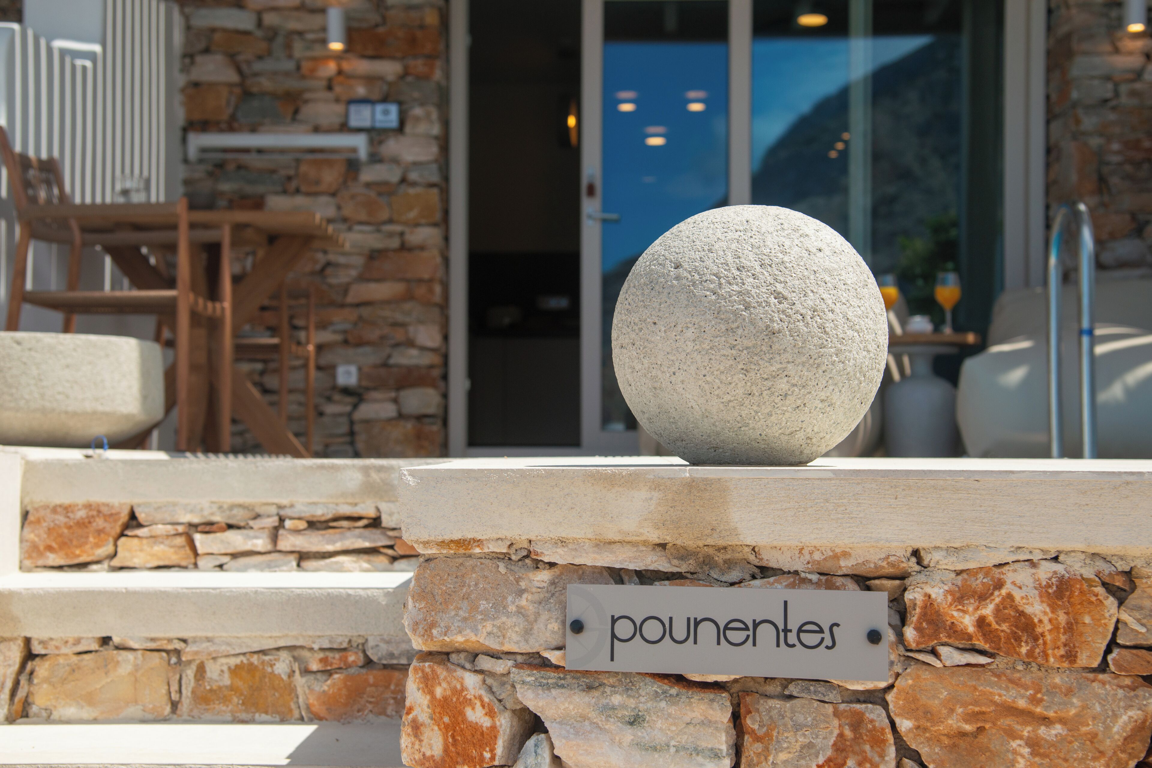 A stone wall with a sign reading "pouentres" and a stone sphere on top.