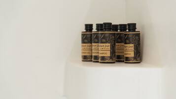 Una fila de botellas negras con diseños y etiquetas florales, cada una identificada con diferentes nombres de productos como 'Shampoo' y 'Conditioner'.
