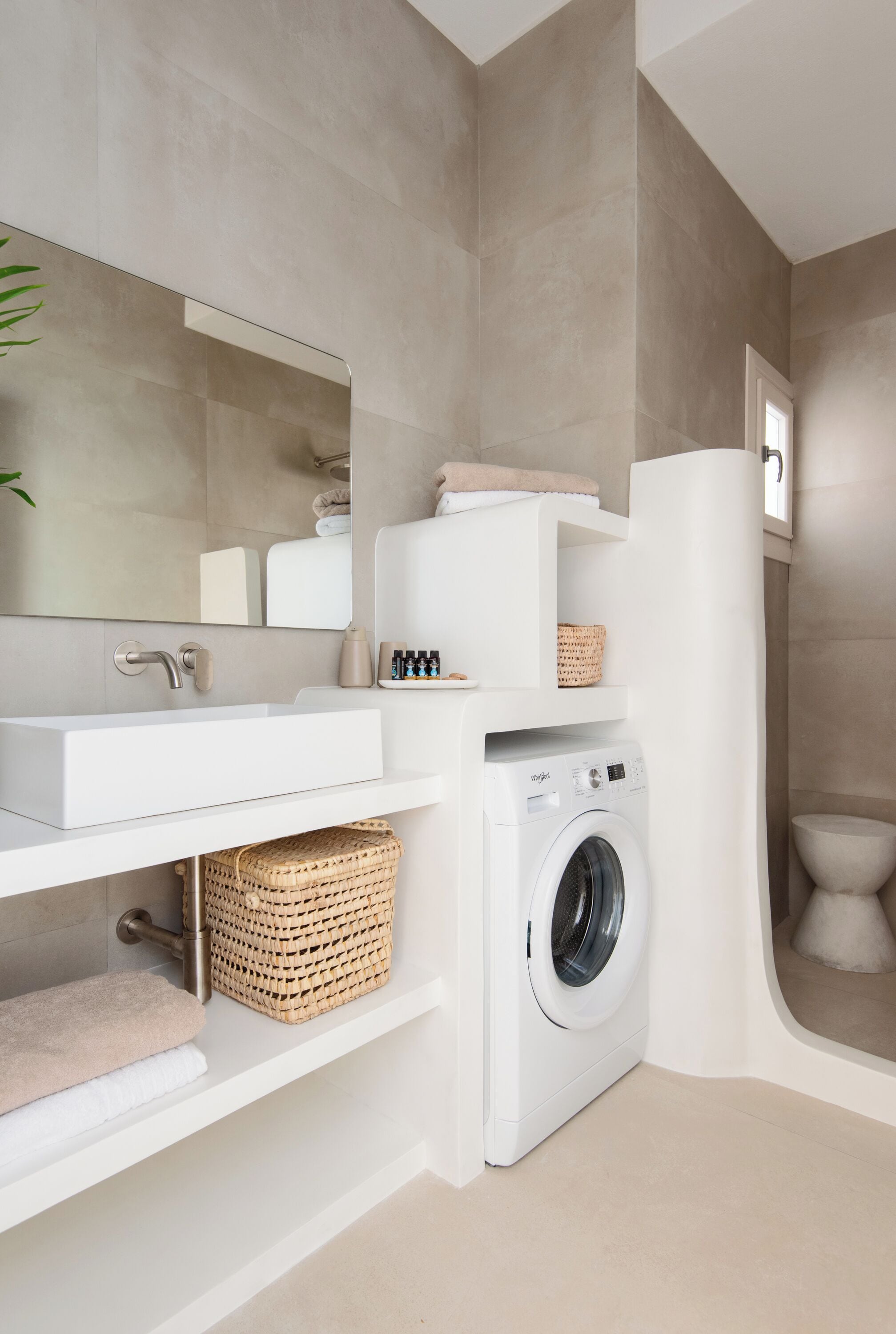 Une salle de bain moderne équipée d’un lavabo intégré, d’un lave-linge et de toilettes.