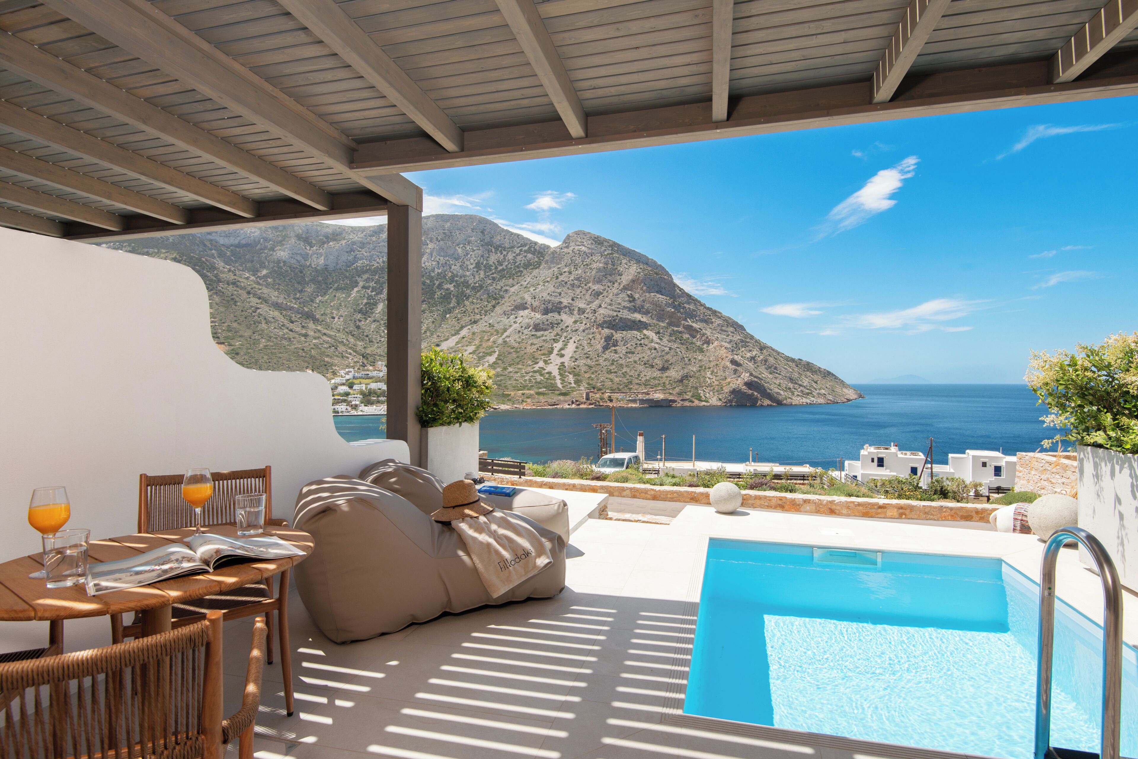 A terrace with a pool, seating, and a view of the sea and mountains.
