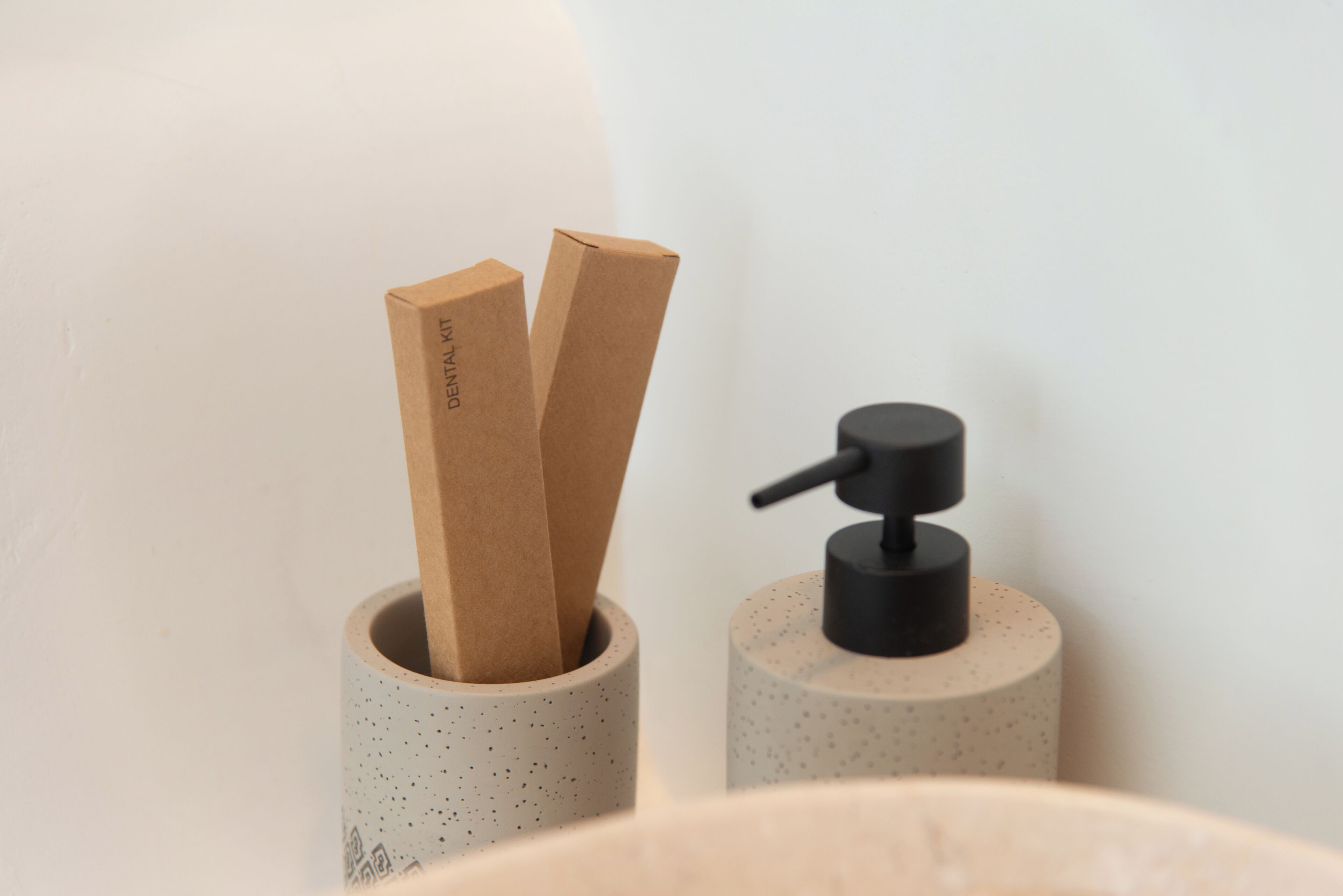 Two cylindrical containers, one with a speckled pattern and the other plain, each holding a brown paper bag and a black pump.