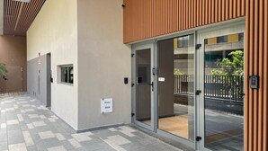 A modern building entrance with a checkered tile floor, a glass door, and a wooden panel on the right. - Helbor Edition Vila Madalena (São Paulo)