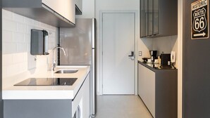 A modern kitchen with a stainless steel refrigerator, a built-in oven, and a sink. There is a door leading to another room and a sign on the wall indicating 'Historic Route 66'. - Helbor Edition Vila Madalena (São Paulo)