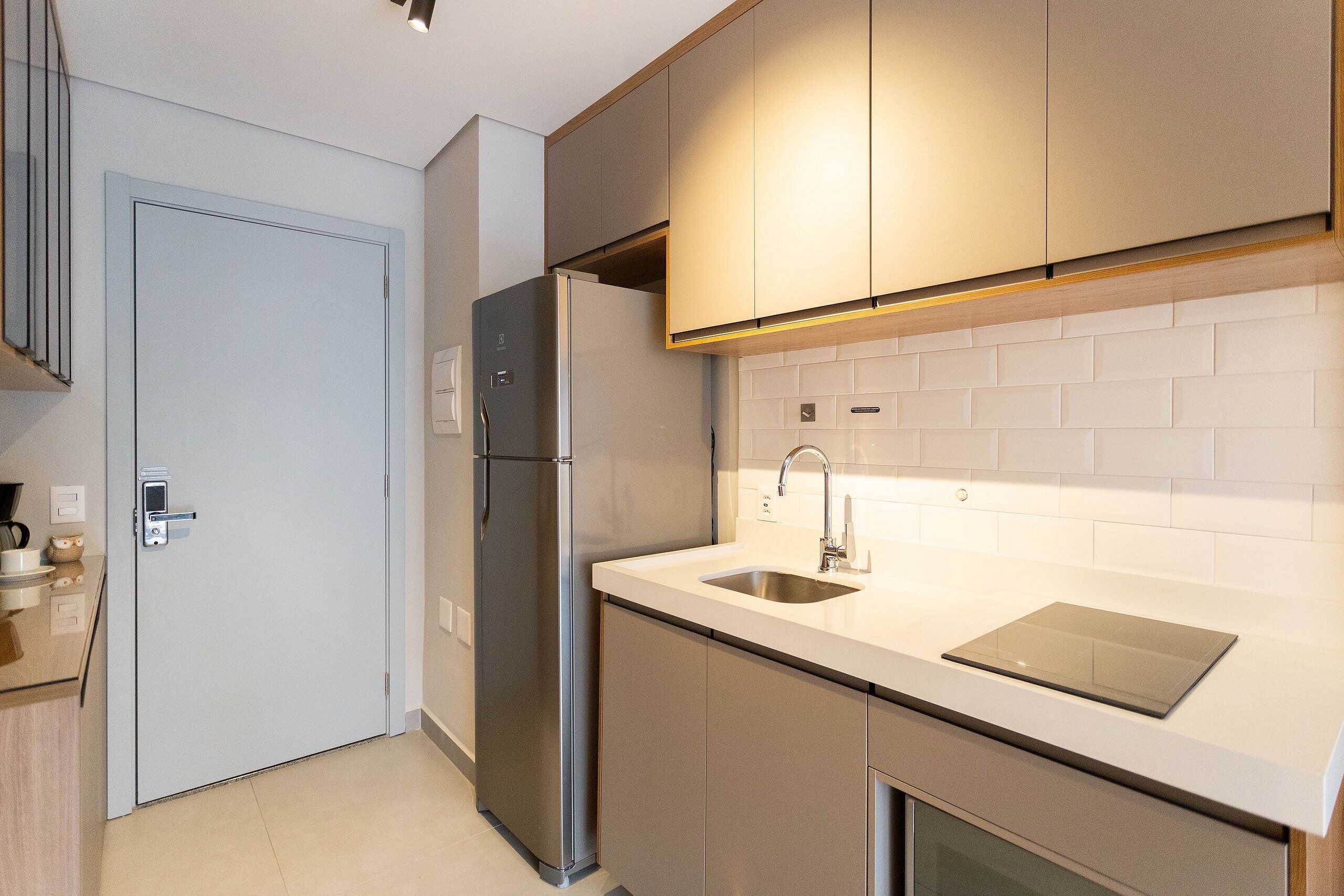 A modern kitchen with a stainless steel refrigerator, a sink, and a built-in oven.