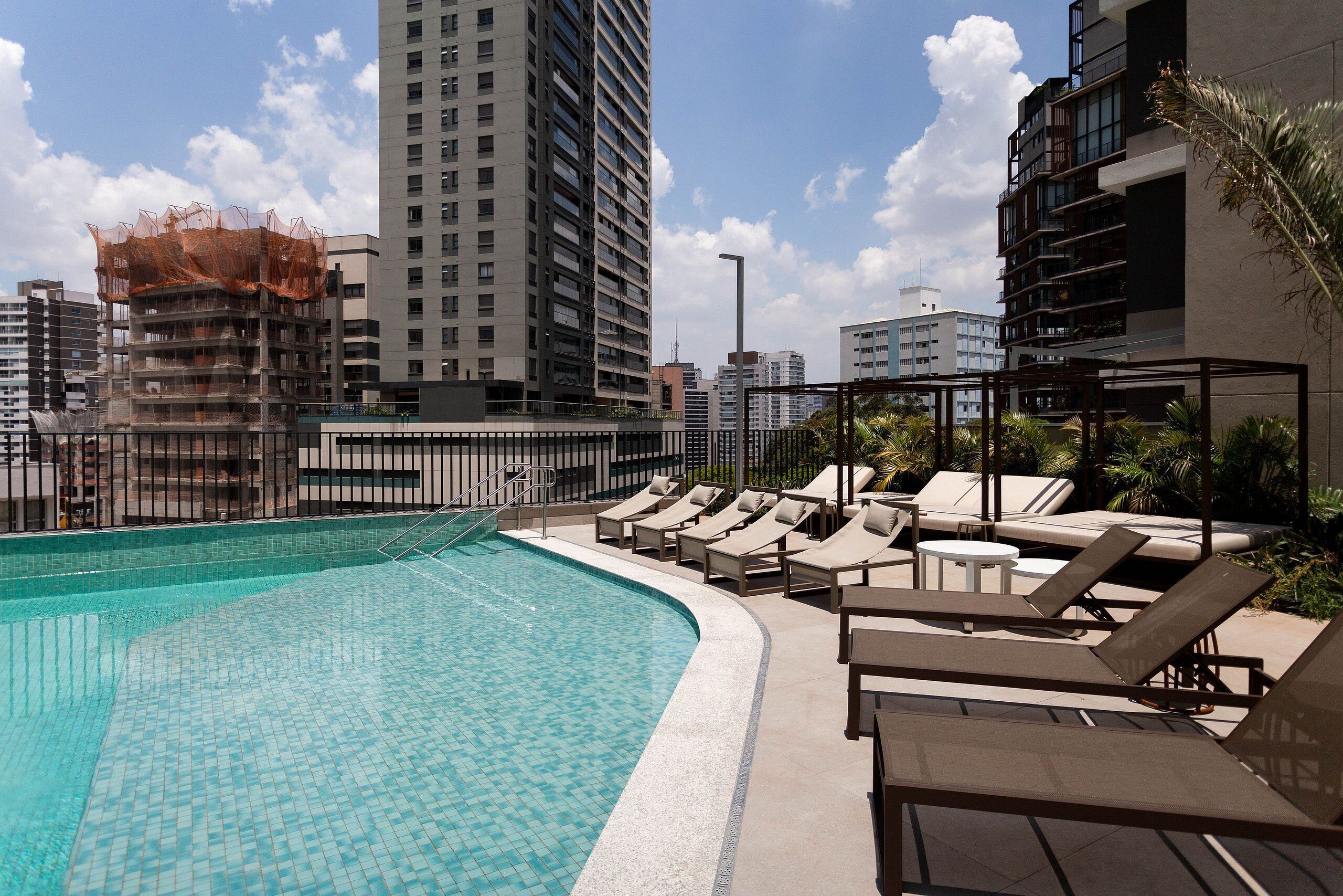 Una piscina al aire libre, sombrillas, sillones reclinables de piscina