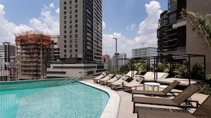 A rooftop pool with lounge chairs and a view of surrounding buildings. - Helbor Edition Vila Madalena (São Paulo)
