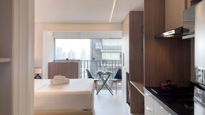 A modern hotel room with a bed, a small dining area, and a kitchen. - Helbor Edition Vila Madalena (São Paulo)