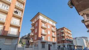 A multi-story residential building with balconies, a gated entrance, and parked cars on the street. - Casa Paradiso by Wonderful Italy (Turin)
