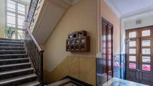 A marble staircase with a geometric patterned floor, a wooden display case, and a wooden door with glass panels. - Casa Paradiso by Wonderful Italy (Turin)